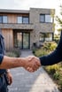 Zwei Männer geben sich vor einem modernen Einfamilienhaus die Hand.