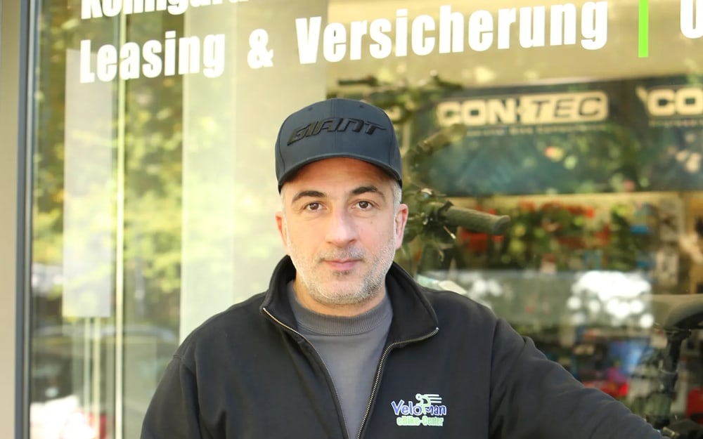 Vardan Abrahamyan vor dem Schaufenster mit der Aufschrift Leasing & Versicherung