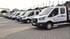 Eine Reihe weißer Ford Transit Firmenwagen der Firma Bedachungen Schmidt parkt auf einem gepflasterten Betriebshof.