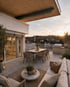 Moderne Dachterrasse mit Esstisch, Lounge-Möbeln und Blick über die Stadt bei Sonnenuntergang.