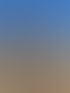 Eine lächelnde Frau mit blonden Strähnen streichelt den Kopf eines braunen Pferdes vor blauem Himmel.