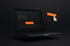 Schwarzer Laptop mit dunklem Bildschirm und daneben ein 3D-Symbol für Webdesign mit orangefarbenem Lineal und Mauszeiger.