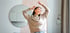 Woman in beige sweater stretching, highlighting back pain relief.