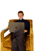 Ein Mann im Rollkragenpullover sitzt auf einem Sessel und arbeitet auf einem Laptop.