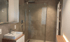Modernes Badezimmer mit begehbarer Dusche, Waschbecken, Spiegel und Handtuchhalter.
