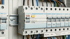 Elektrischer Sicherungskasten mit mehreren Hager R-Schutzschaltern und farbigen Kabeln.