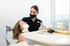 Zahnärztin mit schwarzer Maske lächelt eine Patientin während einer Behandlung in einer hellen Zahnarztpraxis an.