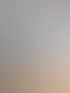 Moderner Balkon mit zwei grünen Stühlen und einem runden Tisch bietet Ausblick auf eine Wohnsiedlung unter blauem Himmel.