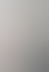 Eine Frau mit tätowiertem Arm greift in einem Geschäft nach einem Produkt aus einem Regal, im Hintergrund ist ein Banner zu sehen.