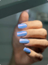 Gepflegte Hand mit hellblauen, quadratisch gefeilten Fingernägeln und schimmerndem Chrome-Finish.