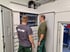 Zwei Männer in Arbeitskleidung betrachten einen offenen ELAS-Schaltschrank mit vielen Kabeln und Anschlüssen.