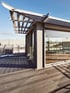 Beispiel Nachverdichtung - Dachterrasse mit Holzboden und Glasgebäude unter blauem Himmel.