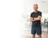 Lächelnde Frau in Sportkleidung läuft auf einem Laufband, mit Fitness-Trackern am Handgelenk.