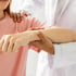Doctor assists patient’s arm, aiding mobility restoration.