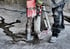Arbeiter bohrt mit einer roten Kernbohrmaschine ein Loch in eine nasse Betonfläche.