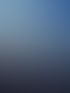 Frau meditiert im Schneidersitz auf einem Felsen mit Blick auf eine bergige Landschaft unter blauem Himmel.