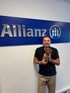Ein Mann hält einen braunen Dackel vor einer blauen Allianz-Wandbeschriftung.
