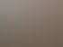 Orangefarbene Warnschutzjacken liegen auf Arbeitstischen und Kleiderständern in einer hellen Textilwerkstatt mit Maschinen.