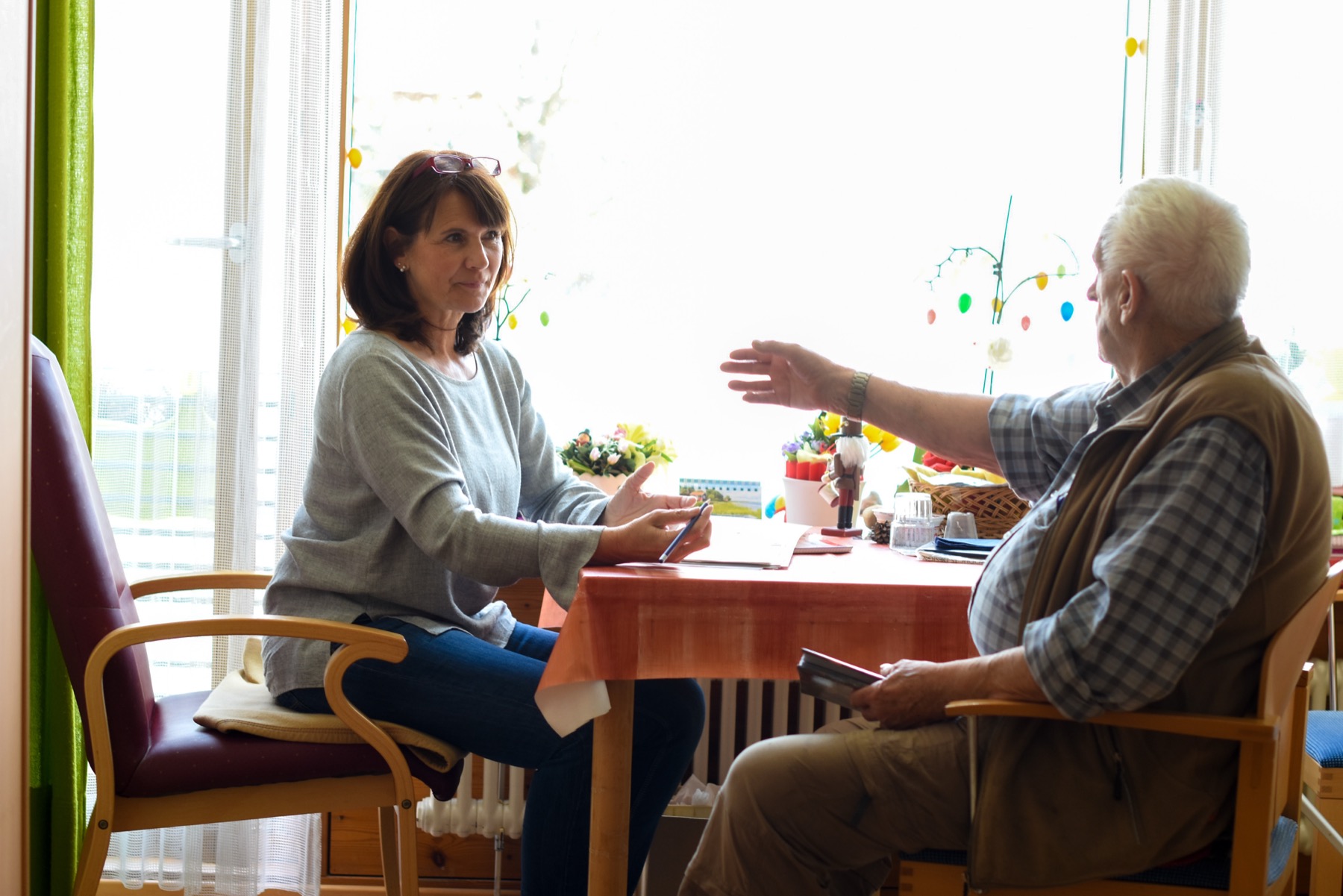 Mitarbeiterin im vertrauensvollen Gespräch mit einem Senior