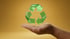 Eine Hand hält ein schwebendes, transparentes, grünes Recycling-Symbol vor einem gelb-orangen Hintergrund.