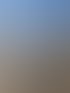 Eine blonde Frau mit Brille und ein Kind sitzen in Liegestühlen unter blauem Himmel am Hafen.