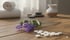 Lavendelzweig mit kleinen violetten Blüten neben weißen runden Pillen auf einem Holztisch mit Spa-Elementen.