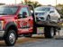 Towing Sandy flatbed towing service securing a damaged sedan onto a rollback tow truck for safe vehicle transport.