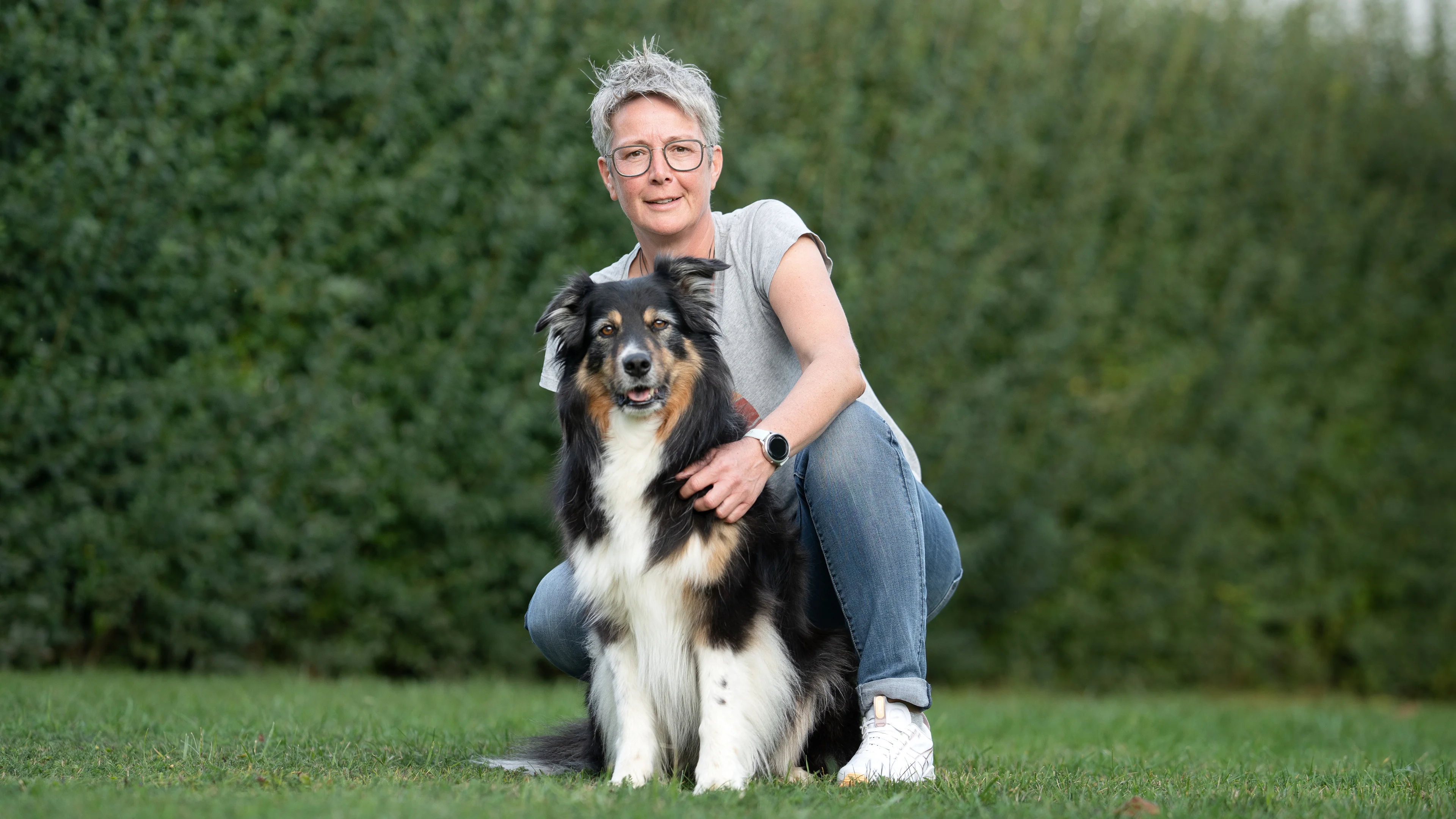 Angelika Hellmannsberger mit ihrem Hund vor einer Hecke