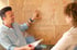 Markus Spenger zeigt auf ein Flipchart mit den Wörtern „Rolle“, „Einstellungen“, „Fähigkeiten“, „Handlungen“, „Kontext“.