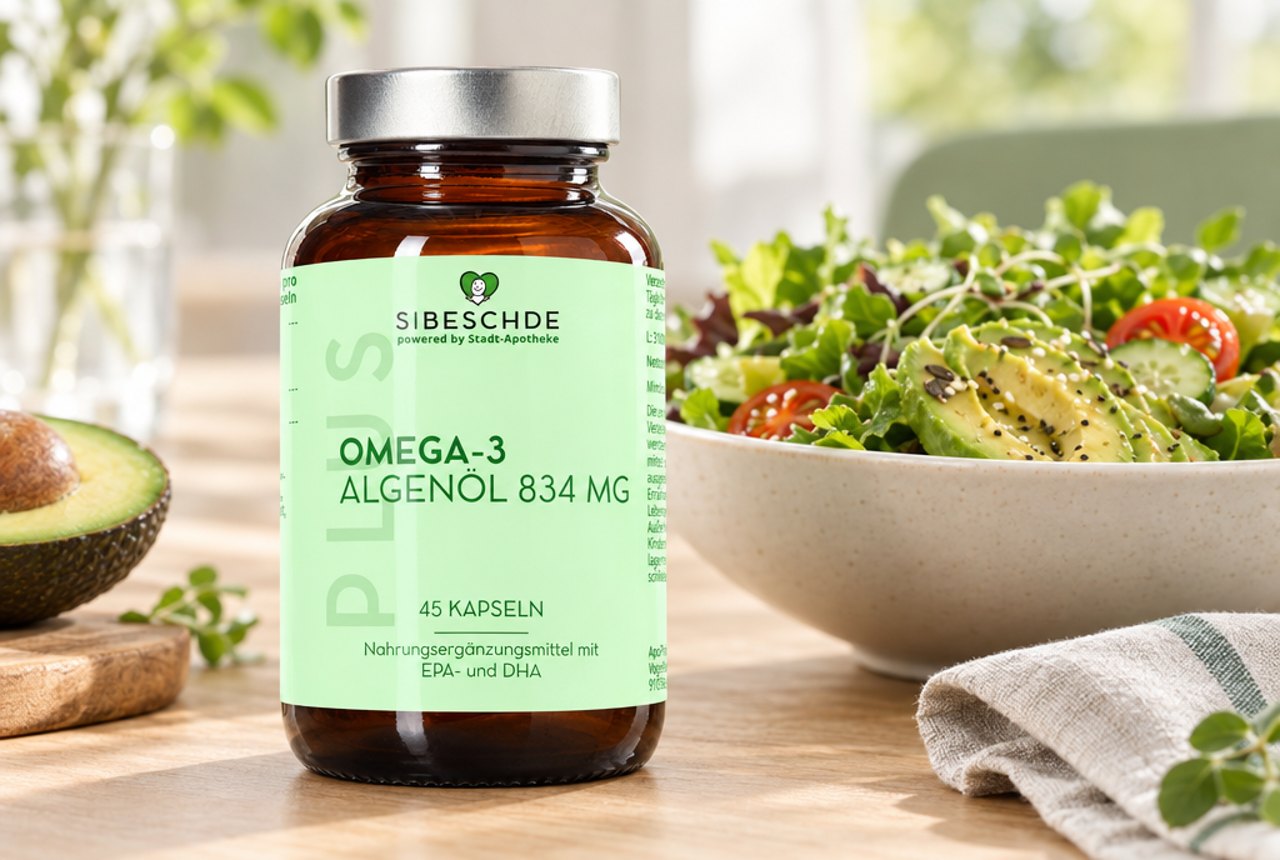S|BESCHDE Omega-3 Algenöl 834 mg auf einem Esstisch neben einer Salatschüssel mit Avocado und einer Leinenserviette