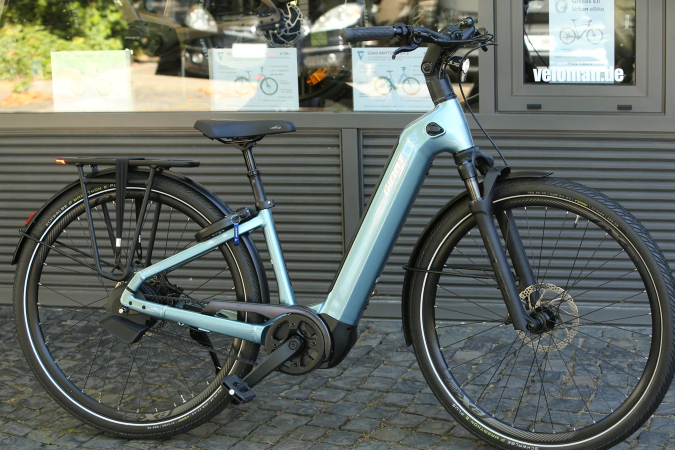 Türkises eBike mit Trapezrahmen vor dem Schaufenster