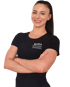 Lächelnde Bianca Personal Trainerin mit verschränkten Armen im schwarzen T-Shirt vor schwarzem Hintergrund.
