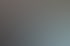 Eine rothaarige Frau mit Tattoos sitzt in einem Atelier voller Gemälde und schaut in einen großen Spiegel.