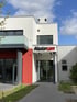Modernes weißes Gebäude mit roter Akzentwand und "Mastercam"-Schild über dem Eingang.