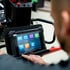 Ein Mann tippt auf einem Tablet mit App-Symbolen, das an einem Diagnosegerät befestigt ist.