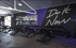 Fitnessstudio mit Ellipsentrainern, einem runden Lichtring an der Decke und einer Wendeltreppe im Hintergrund.
