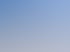 Gelber Gabelstapler lädt weiße Ziegelsteine auf Paletten unter blauem Himmel.