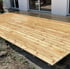 Frisch verlegte Holzterrasse aus hellen Holzdielen vor einer weißen Hausfassade mit großen Glasschiebetüren.
