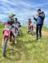 Ein Motocross-Fahrer mit Helm und der Nummer 291 sitzt auf einem roten Motorrad, während ein Trainer zu ihm spricht.