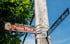 Street signs for "Historic District Roslyn Place" and "Ellsworth Ave" on a wooden pole against a blue sky.
