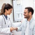 A doctor smiles and shakes hands with a male patient.