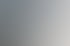 Mann im blauen Sakko steht an einem weißen Tisch und spricht zu zwei sitzenden Personen in einem modernen Besprechungsraum