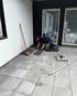Mitarbeiter verlegt große graue Platten auf der Terrasse vor dem Haus