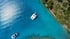 Luftaufnahme von zwei weißen Yachten in einer Bucht mit kristallklarem, türkisfarbenem Wasser und bewaldeter Küste.