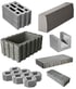 Various grey concrete construction materials including hollow blocks, curb stones, and interlocking paving stones.