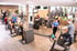 Menschen trainieren an verschiedenen Fitnessgeräten in einem modernen Fitnessstudio.