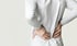 A woman is in pain, holding her back and seeking sciatica relief.