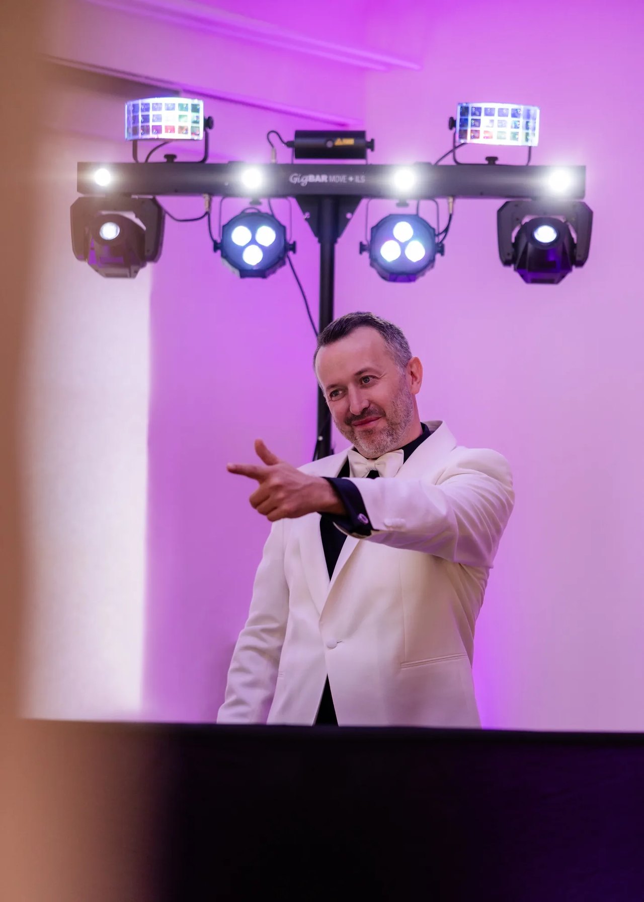 DJ Michael Newell im weißen Dinnerjacket am DJ-Pult unter der Lichtanlage