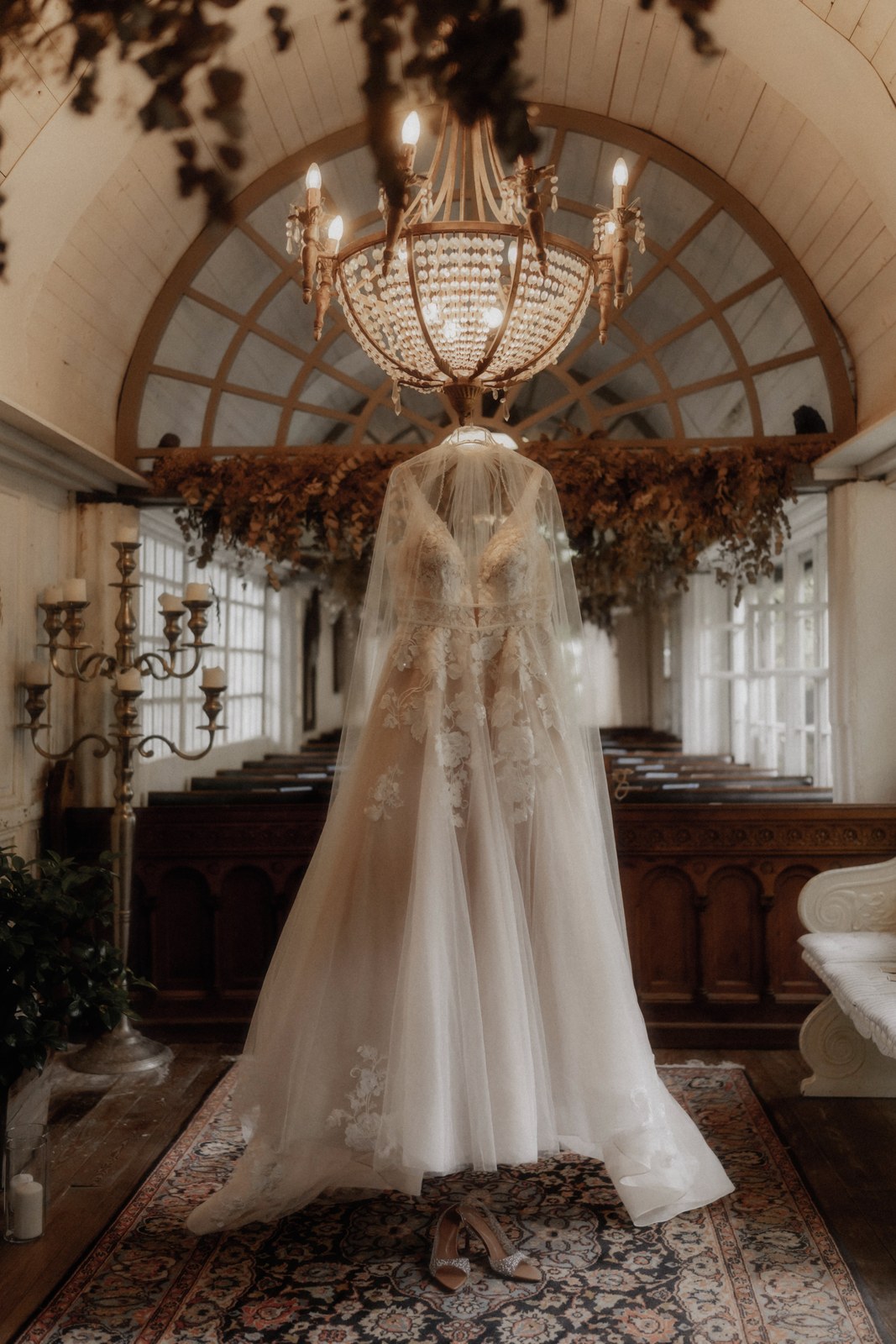 Braut im fließenden Brautkleid unter einem prächtigen Kronleuchter in einem barocken Festsaal.