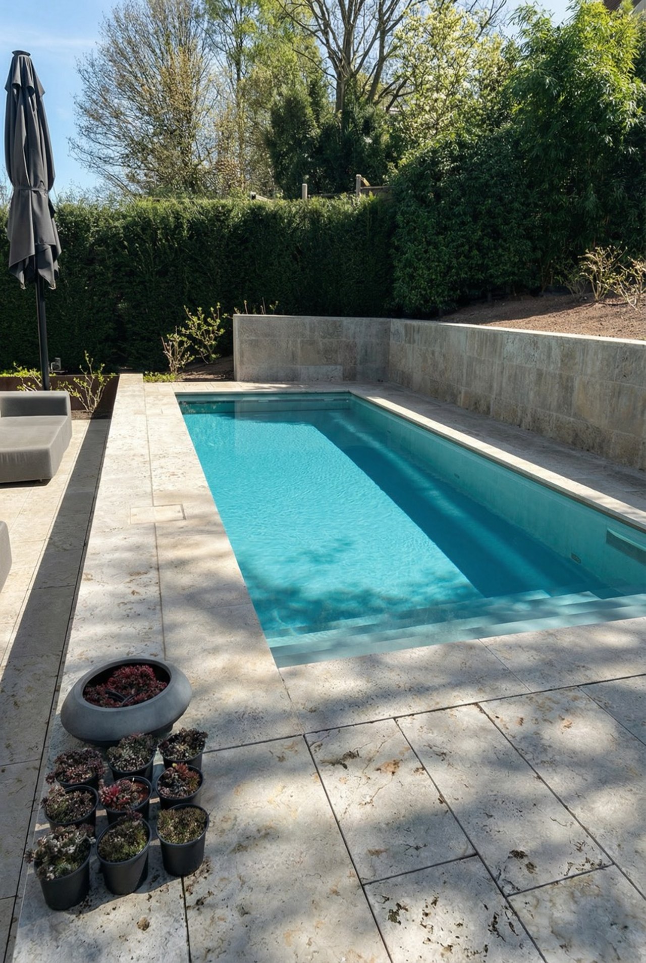 Blauer Swimmingpool mit Steinterrasse im Grünen